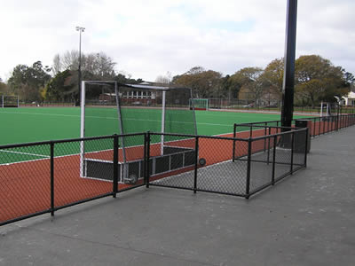 A short black chain link fence with round posts is installed on the concrete ground at a football court.